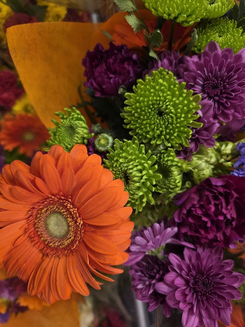 A vibrant bouquet of fresh flowers arranged by Kennington Florist, featuring a large orange gerbera daisy with soft, layered petals and a central disk, surrounded by clusters of green chrysanthemums w
